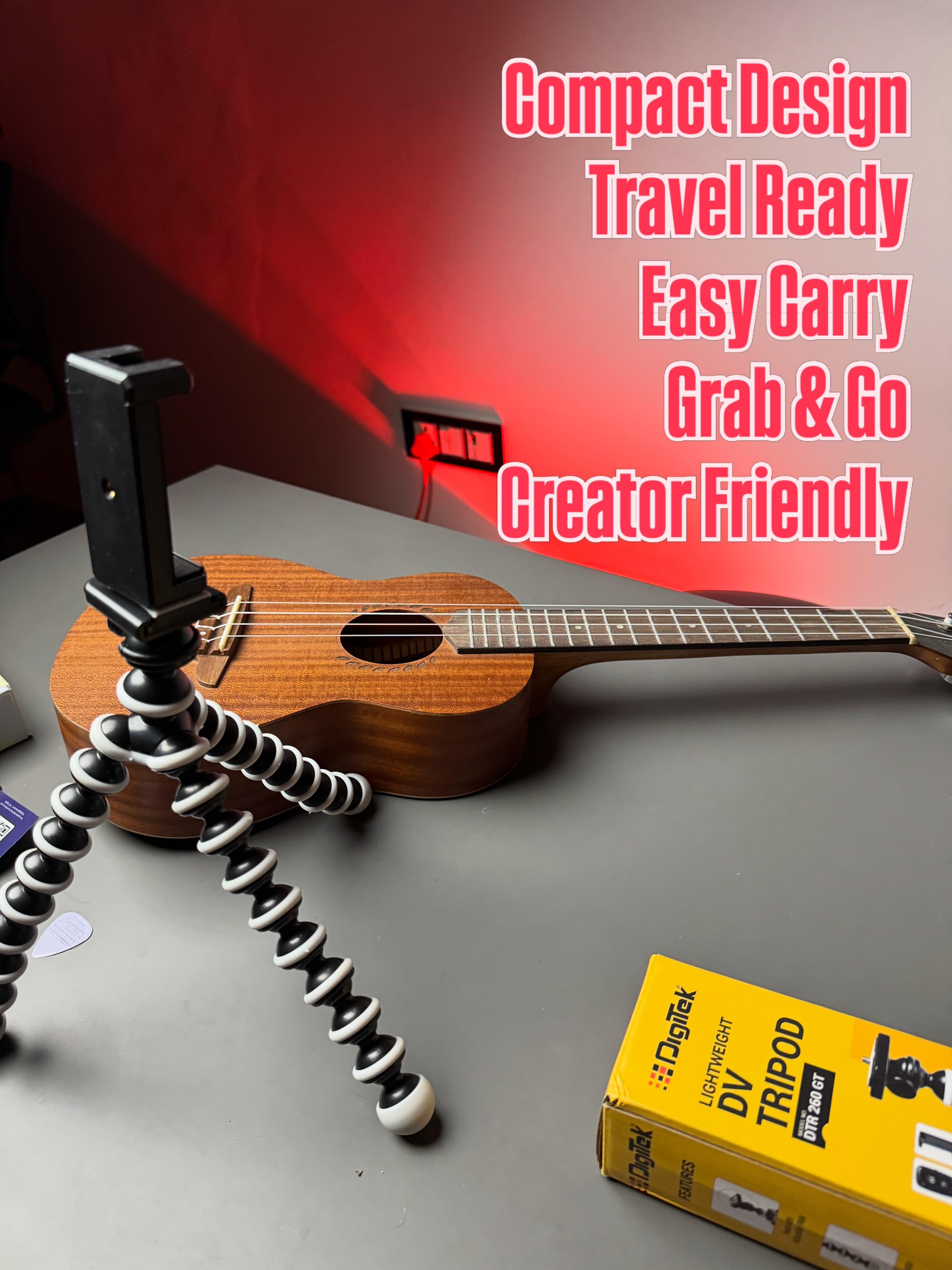 The Digitek gorilla tripod with phone mount standing on a desk next to a ukulele