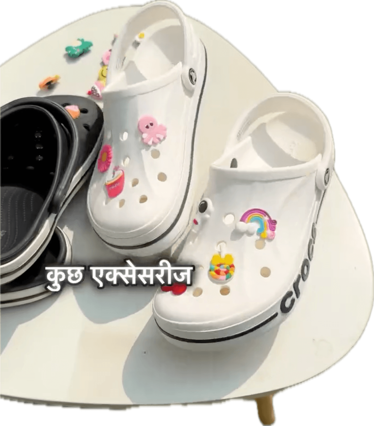 A pair of white Crocs decorated with charms, held up outdoors
