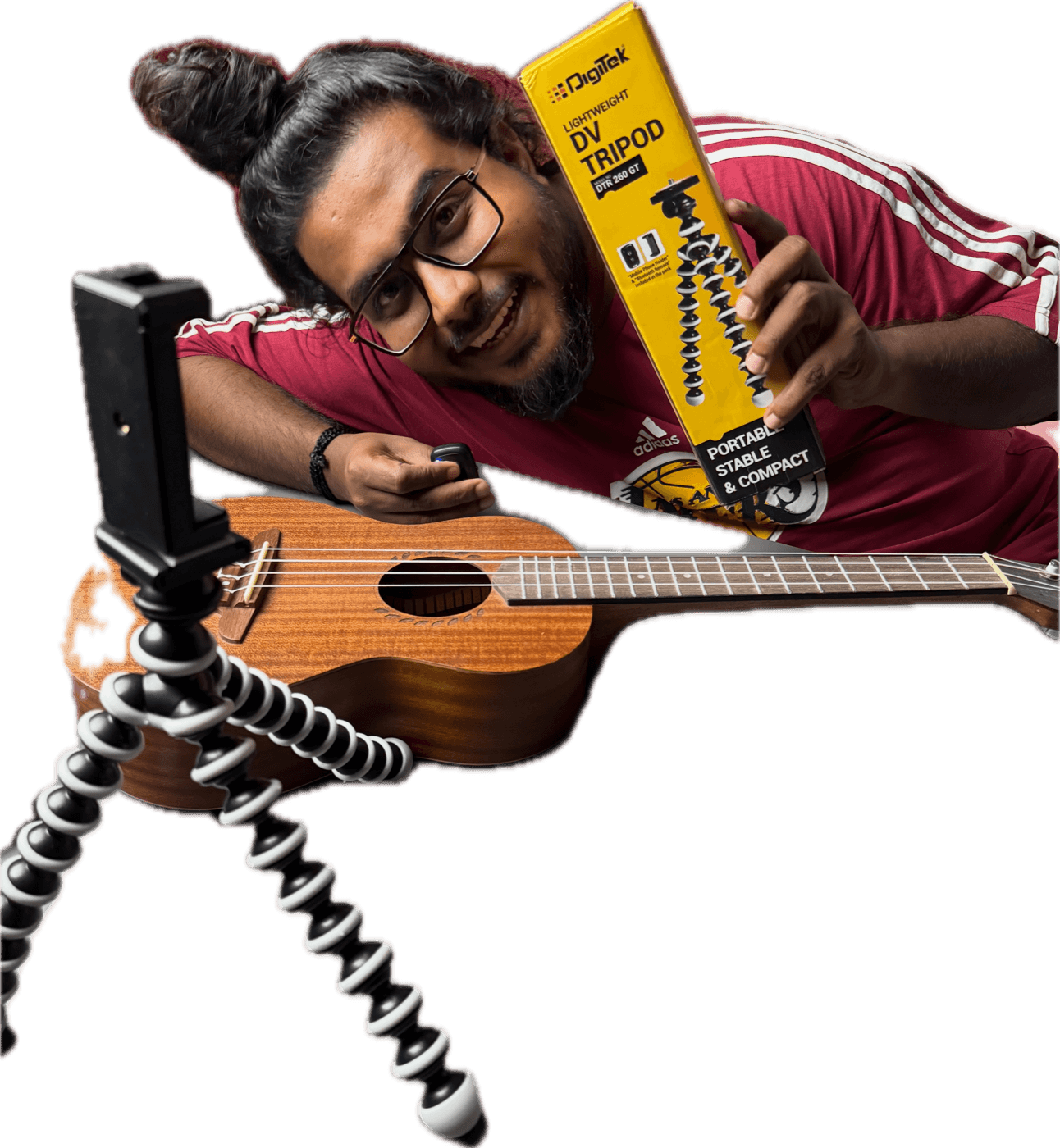Akio holding the Digitek tripod box beside a flexible gorilla tripod with a phone holder and a ukulele